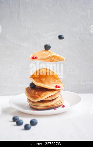 Frisch gekochte Pfannkuchen und Beeren mit Honig, Walnuss zum Frühstück fliegen. Gleichgewicht schwimmende Lebensmittel Konzept. Stockfoto