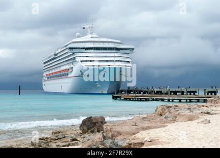 Touristen, die vom Kreuzschiff hin- und herlaufen zur Grand Turk Insel unter dem regnerischen dunklen Himmel (Turks- und Caicos-Inseln). Stockfoto