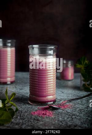 Vorbereiteter Matcha-Tee in einem klaren Glas. Ein köstliches Getränk aus japanischem rosa Teepulver. Vertikale Position Stockfoto