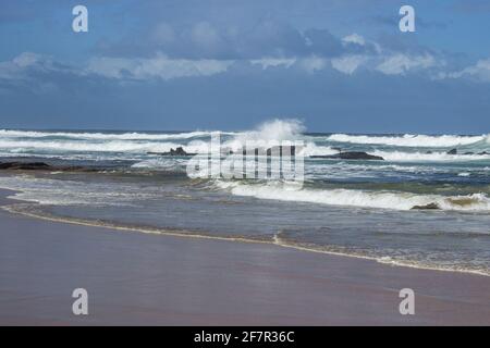 Wellen brechen an einem isolierten Felsvorsprung am Strand der Stadt Wilderness, an der Südküste Südafrikas Stockfoto