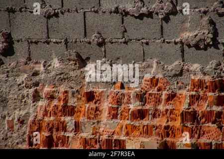 Wand aus gebrochenen roten Ziegeln und grauen Beton Hohlblock Ziegel Stockfoto