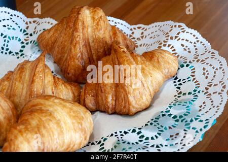 Konzept „Guten Morgen“. Frisch gebackene Croissants auf einem Teller mit Serviette. Warme, frische Buttercroissants und Brötchen Stockfoto