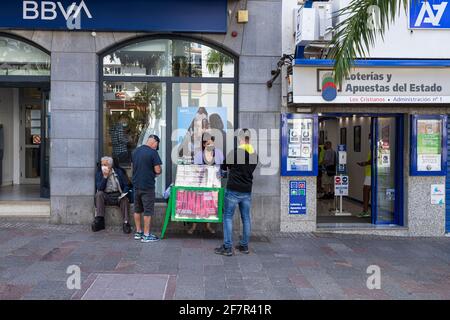 EINMAL Lotterieverkäufer auf der Straße vor der BBVA-Bank und offiziellem Lotteriebüro in Los Cristianos, Teneriffa, Kanarische Inseln, Spanien Stockfoto