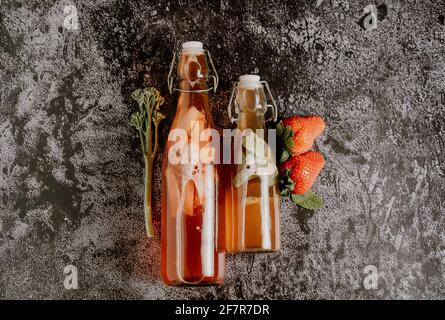 Isolierte Flaschen mit hausgemachtem Kombucha, einem Brühfruchttee mit Probiotika, Bakterien und Hefe. Zweite Gärung mit Erdbeeren und Minze mit Jahrgang Stockfoto