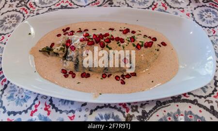 Mexikanisches Gericht, Chiles en nogada. Gefüllte Poblano-Paprika in Walnusssauce mit Granatapfelkernen. Stockfoto