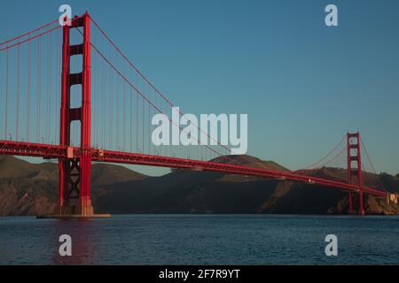 Die Sonne am frühen Morgen erhellt die Ostseite der legendären Golden Gate Bridge von San Francisco, wie man sie von Fort Point aus sieht Stockfoto