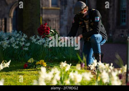 Edinburgh, Schottland, Großbritannien. 9. April 2021. Heute fliegen in Edinburgh Flaggen am Halbmast, als Prinz Philip, der Herzog von Edinburgh, starb. PIC; Frau legt Blumenschmuck im Garten neben dem Palast von Holyroodhouse. Iain Masterton/Alamy Live News Stockfoto