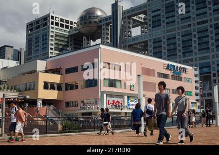 Horizontale Ansicht von Menschen, die in Minato City mit dem Fuji TV-Gebäude im Hintergrund spazieren, Odaiba Island, Tokio, Japan Stockfoto