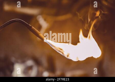 Gasbrenner mit brennender Flamme aus der Nähe auf dem Hintergrund einer Industriewerkstatt. Stockfoto