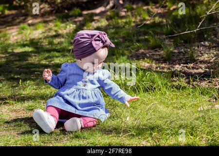 Nettes Baby Mädchen im Freien im Frühling auf Gras Stockfoto