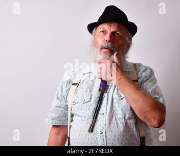 Nachdenklicher älterer kaukasischer bärtiger Mann mit schwarzem Hut Weißer Hintergrund Stockfoto