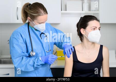 Nahaufnahme einer jungen Frau mit schützender Gesichtsmaske, die geimpft wird, Coronavirus-Konzept. Hochwertige Fotos Stockfoto