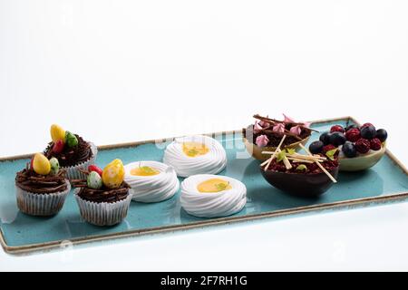 Auswahl an verschiedenen süßen Cupcakes, Keksen und gefüllten Schokoladeneiern auf handgefertigtem Meeresboden Stockfoto
