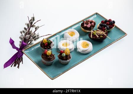 Auswahl an verschiedenen süßen Cupcakes, Keksen und gefüllten Schokoladeneiern auf handgefertigtem Meeresboden Stockfoto