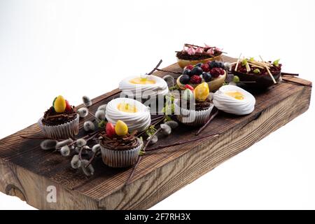 Auswahl an verschiedenen süßen Cupcakes, Keksen und gefüllten Schokoladeneiern auf Holzbrett Stockfoto