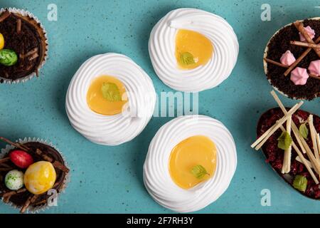 Auswahl an verschiedenen süßen Cupcakes, Keksen und gefüllten Schokoladeneiern auf handgefertigtem Meeresboden Stockfoto