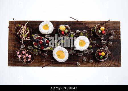 Auswahl an verschiedenen süßen Cupcakes, Keksen und gefüllten Schokoladeneiern auf Holzbrett Stockfoto