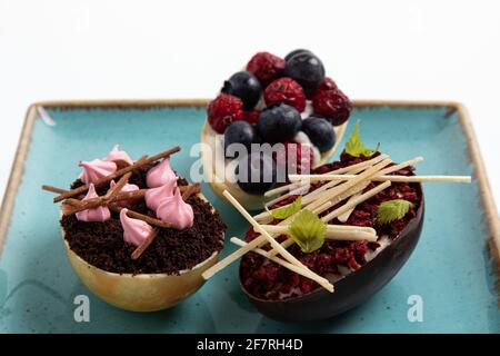 Auswahl an verschiedenen süßen Cupcakes, Keksen und gefüllten Schokoladeneiern auf handgefertigtem Meeresboden Stockfoto