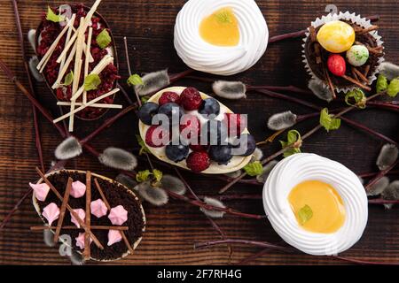 Auswahl an verschiedenen süßen Cupcakes, Keksen und gefüllten Schokoladeneiern auf Holzbrett Stockfoto
