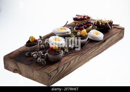 Auswahl an verschiedenen süßen Cupcakes, Keksen und gefüllten Schokoladeneiern auf Holzbrett Stockfoto