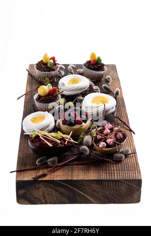 Auswahl an verschiedenen süßen Cupcakes, Keksen und gefüllten Schokoladeneiern auf Holzbrett Stockfoto
