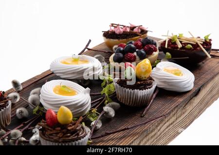 Auswahl an verschiedenen süßen Cupcakes, Keksen und gefüllten Schokoladeneiern auf Holzbrett Stockfoto