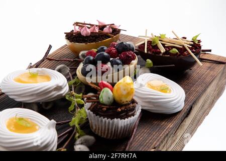 Auswahl an verschiedenen süßen Cupcakes, Keksen und gefüllten Schokoladeneiern auf Holzbrett Stockfoto