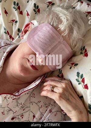 Ältere Frau, die mit einer Augenmask in Flanelllaken schläft, USA Stockfoto