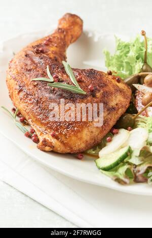 Würziges Hühnerbein mit frischem Salat auf hellem Hintergrund. Nahaufnahme. Stockfoto
