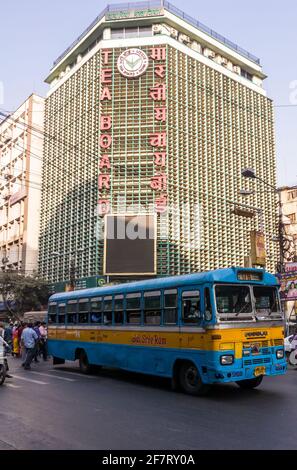 Kalkutta, Westbengalen, Indien - Januar 2018: Ein blau-gelber Bus für den öffentlichen Nahverkehr, der an der alten Architektur des Tea Board-Gebäudes auf dem Th vorbei fährt Stockfoto