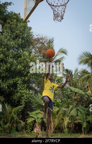 Varanasi, Indien. 10-14-2019. Ein männlicher Jugendlicher ist in der Luft, während er mit dem Ball springt, um nach dem Ende des Spiels in der Schule im Korb zu Punkten Stockfoto