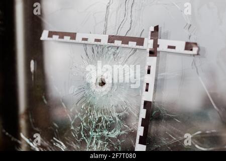 Einschusslöcher in einem Glasfenster, das mit einem gekennzeichnet ist Polizeiband Stockfoto