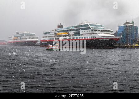 Auto- und Passagierküstenfähren Trollfjord und Midnatsol am Festningskaien Kai, im Hafen von Bergen, Norwegen. Ein Wintersturm nähert sich. Kleines h Stockfoto