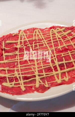 Carpaccio aus Rind mit Mayonnaise-Sauce im klassischen Cipriani-Stil Eine weiße Platte Stockfoto