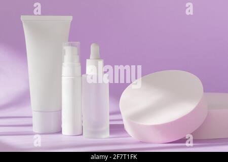 Hautpflege Kosmetikflaschen mockup auf Flieder. Cremedose-Tube, Serum-Glasflaschenschablone, Lotionsspender auf natürlichem Hintergrund mit Schatten, Vorderseite Stockfoto