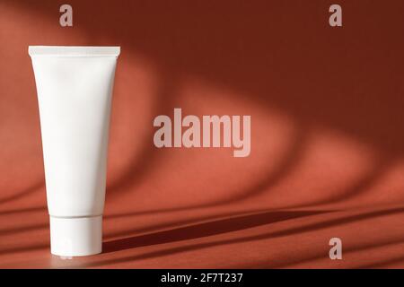 Sonnencreme, Reiniger in weißem Plastikröhrchenschablone auf Hintergrund mit Schatten. Handcreme, Feuchtigkeitscreme, Hautpflege Kosmetik Flasche Mockup. Stockfoto