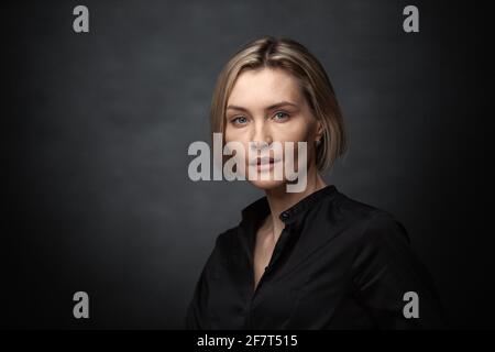 Schöne Frau mittleren Alters auf grauem Hintergrund in eine schwarze Bluse. Stockfoto