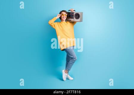 In voller Länge Körper Seite Profil Foto von glücklichen Mädchen zeigen Durch Berühren von Brillen bleibt der Kassettenrekorder in einer lebhaften blauen Farbe isoliert Hintergrund Stockfoto