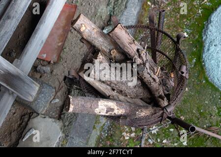 Ein eiserner Korb in einem Ständer mit Holz bereit für die Zündung. Stockfoto