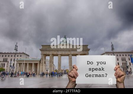 Ein Mann, der ein Schild mit dem Brandenburger Tor in der Hand hält Berlin im Hintergrund Stockfoto