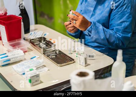 Coronavirus-Impfstoff-Konzept. Arbeitsteam in hellblauer Sicherheitsuniform, Maske und Brille bereiten das Fläschchen und die Spritze des Coronavirus-Impfstoffs vor. COVID-1 Stockfoto