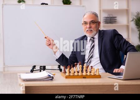 Alter Geschäftsmann Angestellter, der Schach am Arbeitsplatz spielt Stockfoto
