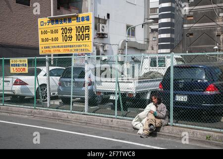 Obdachloser japanischer Mann saß mit seiner Bettdecke vor dem Parkplatz in Shinjuku, Tokio, Japan Stockfoto