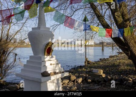 ZUTPHEN, NIEDERLANDE - Mar 30, 2021: Kleine buddhistische Stupa Ornament am Rande des Flusses IJssel in Zutphen, umgeben von Vegetation mit bunten p Stockfoto