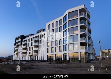 ZUTPHEN, NIEDERLANDE - Mar 30, 2021: Sonnenlicht reflektiert in den Fenstern einer modernen weißen Außenfassade zur blauen Stunde Stockfoto