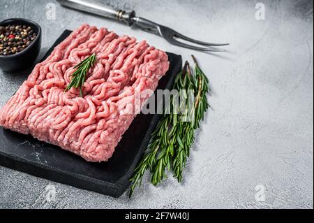 Hackhähnchen oder putenfleisch auf Schneidebrett mit Kräutern. Weißer Hintergrund. Draufsicht. Speicherplatz kopieren Stockfoto