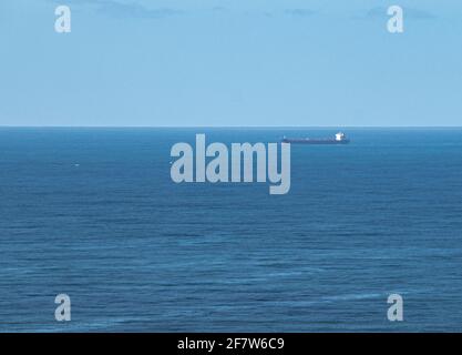 Frachtschiff verlässt den Hafen auf ruhiger See Stockfoto