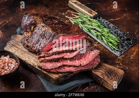 Gebratenes, hängendes, zartes oder in Scheiben geschnittenes Rindersteak auf einem Fleischbrett mit Hackschnitzel. Dunkler Hintergrund. Draufsicht Stockfoto