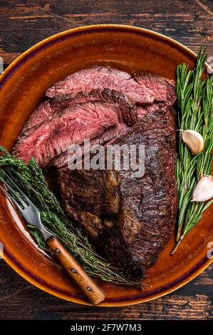 Gerösteter Aufhänger oder Onglet-Rinderfleischsteak in Scheiben auf einem rustikalen Teller mit Hackschnitzel. Dunkler Holzhintergrund. Draufsicht Stockfoto