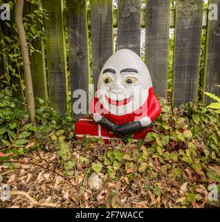 WELLLINGTON, NEUSEELAND - 09. Feb 2021: Ein Ornament von Humpty Dumpty, das auf einer brckigen Wand sitzt, in einem herbstlichen Garten mit einem flügeligen Zaun und Blatt Stockfoto